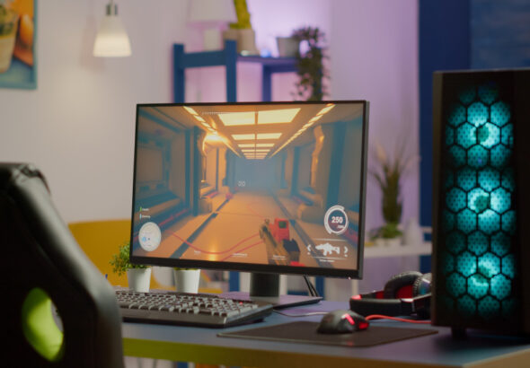 High-performance desktop PC setup with RGB gaming tower, monitor displaying coding or FPS interface, mechanical keyboard, and modern developer workspace