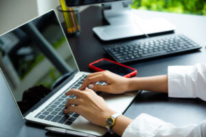 programmer typing code on laptop at modern workspace with smartphone and keyboard
