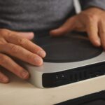 Hands using a compact mini PC with multiple ports, ideal for programming and development setups