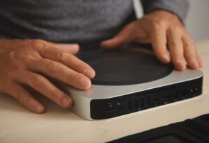 Hands using a compact mini PC with multiple ports, ideal for programming and development setups