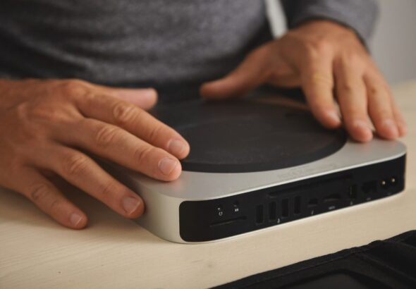 Hands using a compact mini PC with multiple ports, ideal for programming and development setups