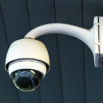 Wall-mounted dome security camera with a protective housing and curved arm