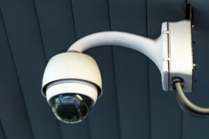 Wall-mounted dome security camera with a protective housing and curved arm
